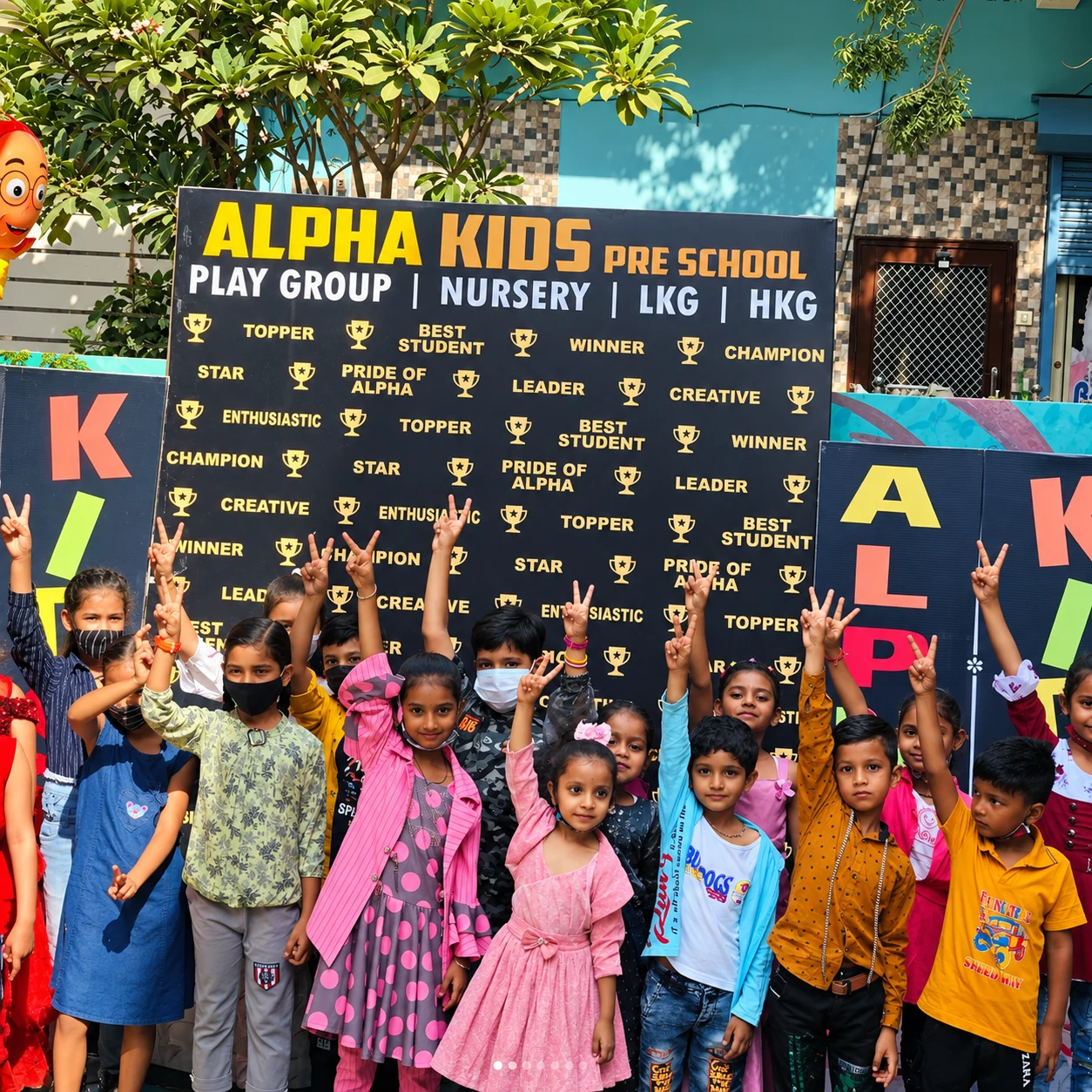 Pre-school students cheering and celebrating in front of Alpha Kids Pre School banner